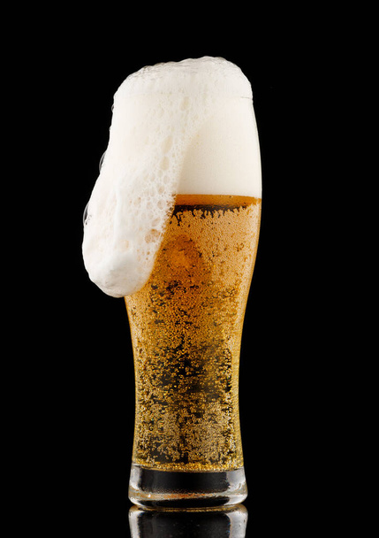 Светло-желтое пиво с пеной на стеклянном черном фоне - Фото, изображение