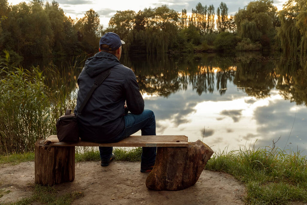 A man sitting in front of a lake. - Foto, afbeelding