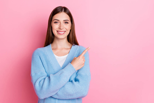 Photo of adorable beautiful positive girl dressed blue knit cardigan arms crossed pointing finger on empty space isolated on pink color background. - Foto, immagini