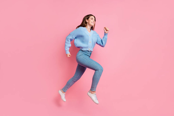 Profile side full length photo of attractive cheerful cute girl running in air clenching fists look at empty space isolated on pink color background. - Fotografie, Obrázek