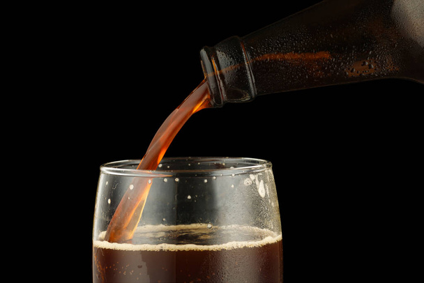 Dark beer is poured into a glass from a bottle - Foto, Imagem