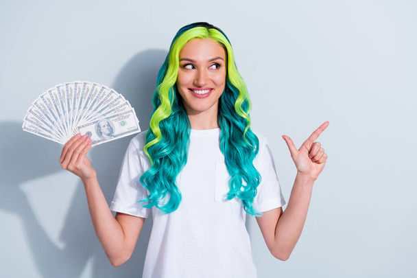 Photo of cute funny vibrant gradient hair girl dressed t-shirt holding money fan pointing empty space isolated white color background. - Фото, изображение