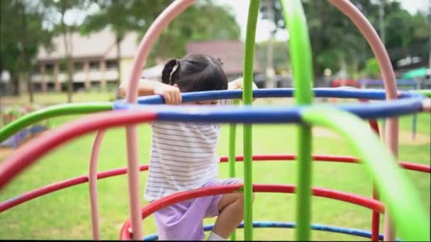 Nette asiatische Mädchen spielen auf dem Schul- oder Kindergartenhof oder Spielplatz. Gesunde Sommeraktivität für Kinder. Kleines asiatisches Mädchen klettert draußen auf dem Spielplatz. Kind spielt auf Spielplatz im Freien. - Filmmaterial, Video