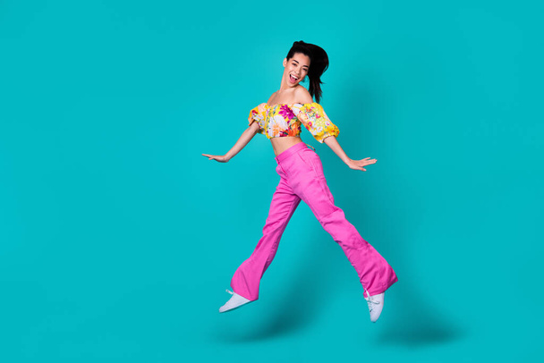 Full length photo of young chinese crazy excited girl jump up air go weekend after work happy isolated on cyan color background. - Fotó, kép