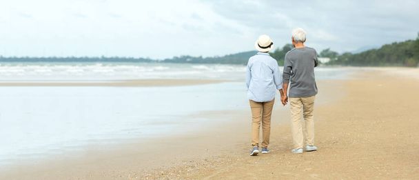 Asian Lifestyle senior couple walking chill on the beach happy in love romantic and relax time after retirement. People tourism elderly family travel leisure and activity after retirement in vacations and summer - Photo, Image