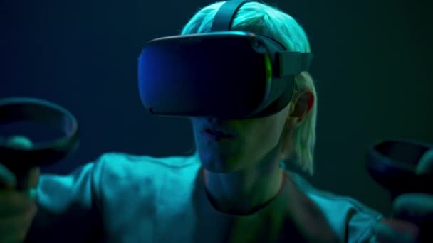 Excited man experiencing handheld trackpads videogame closeup. Impressed gamer using gadget for virtual reality on neon background. Futuristic goggles youngster playing. Future technology concept  - Metraje, vídeo