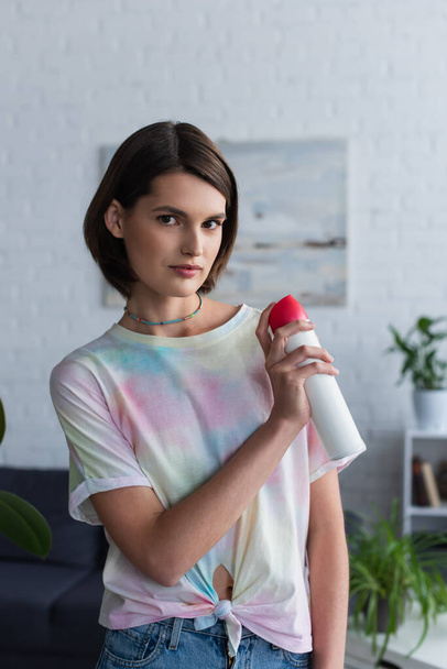 Young woman looking at camera and holding air freshener at home  - Fotó, kép