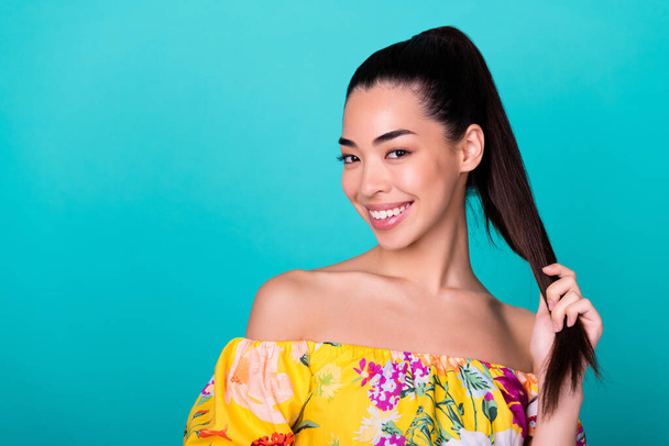 Close up photo of young korean lady touch ponytail haircare product promo wear stylish colorful clothes isolated on cyan color background. - 写真・画像
