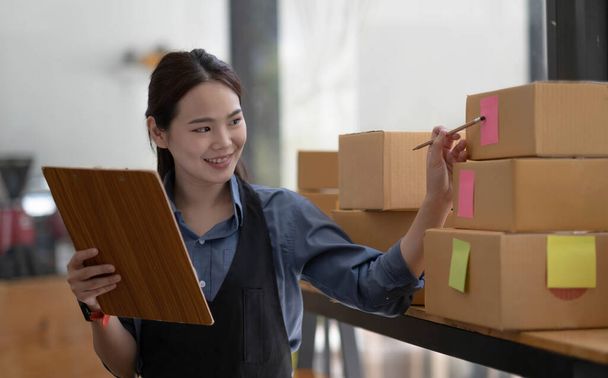 Portrait of Starting small businesses SME owners female entrepreneurs working, box and check online orders to prepare to pack the boxes, sell to customers, sme business ideas online - Photo, Image