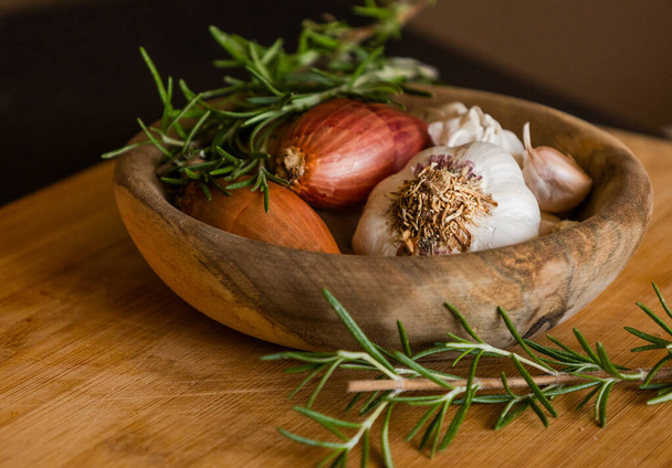 fresh raw onions, garlic, rosemary close up in wooden bowl - Fotografie, Obrázek
