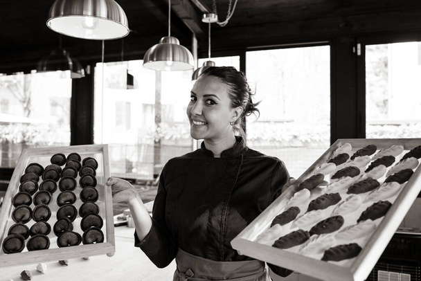 Junge schöne lächelnde Frau zeigt zwei Tabletts mit typisch italienischer frischer Pasta - Sfoglina aus dem Nahen Osten macht frische Pasta in Italien: sardische Culurgiones rechts und Kaffee-Ravioli links - Foto, Bild
