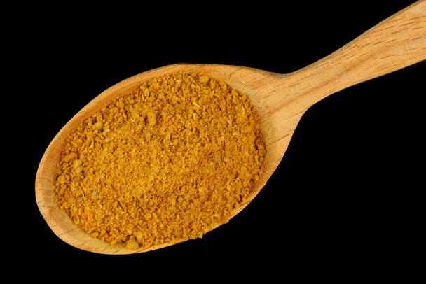 Curry powder seasoning in a wooden spoon black background - Foto, Bild