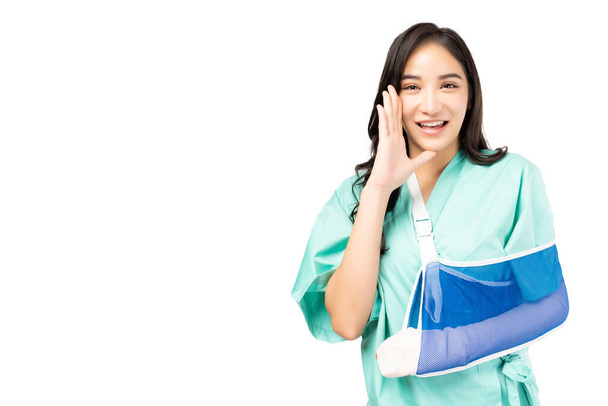 Injured Asian woman put on soft splint due to a broken arm isolated on white background Female wearing patient gown She is shouting Patient Insurance Health care and Personal accident concept - Foto, Imagem