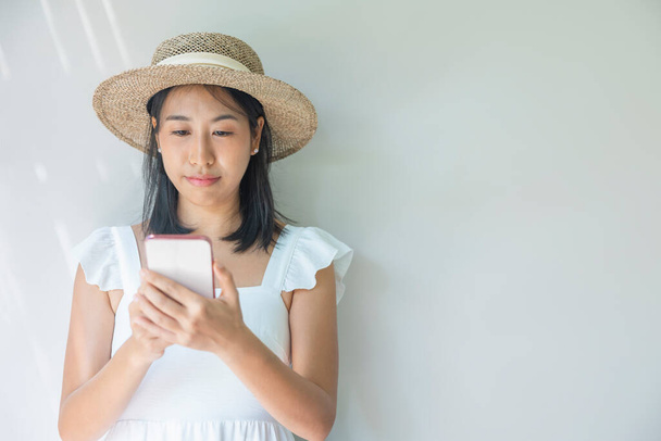 Photo of young woman happy in a white dress and straw hat positive smile use smartphone. Concept of social, technology, travel, rest. - Foto, immagini