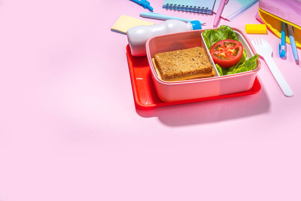 Healthy school meal, back to school concept. Children packed lunch box with balanced diet snack food - yogurt, cereal toast sandwich, apple, fresh vegetable salad, high-colored bright background - Zdjęcie, obraz