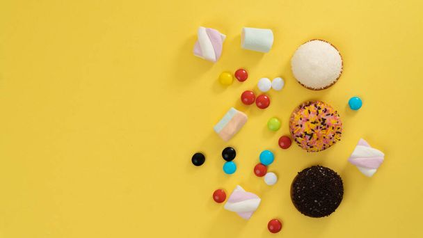Bolos, marshmallows, doces em um contexto amarelo - doces e espaço do texto. Foto de alta qualidade - Foto, Imagem