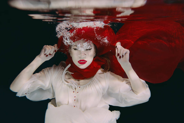 Woman in red hat and red scarf underwater - Foto, Imagem