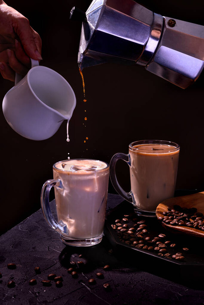 Pouring coffee into an iced filled glass. Dark and moody concept. - Foto, Bild