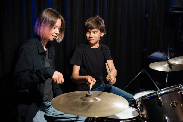 Young woman teaching boy to play drums - Foto, Bild