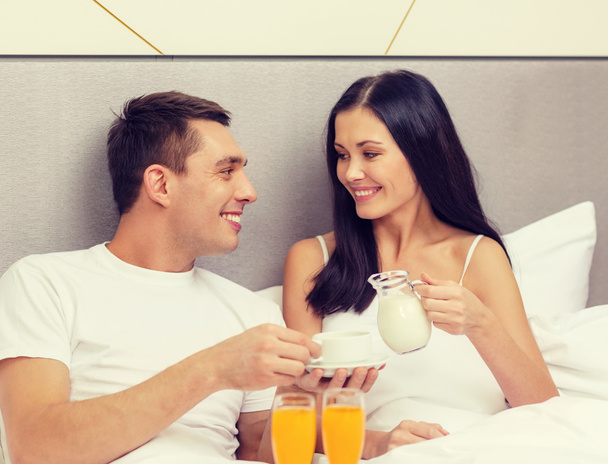 smiling couple having breakfast in bed in hotel - 写真・画像
