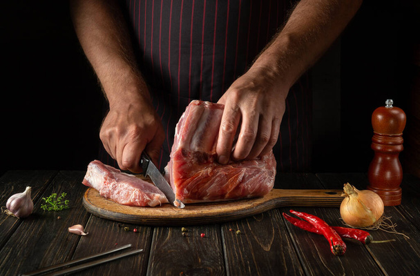 The cook cuts raw ribs on a cutting board before baking. Cooking delicious food in the kitchen. Delicious grill idea. - Foto, immagini
