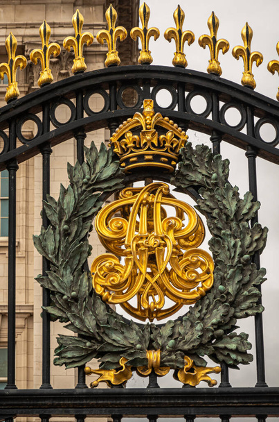 London, England, UK - July 6, 2022: Buckingham Palace. Closeup of Golden Calligraphy and greenish wreath bronze sculpture fixed on fence of front coutyard. - Foto, imagen