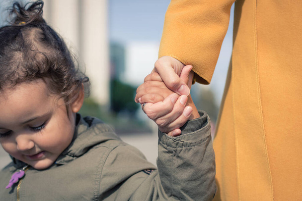 Close up of little girl holding hands with her mother. Mother and daughter bonds.  - Fotoğraf, Görsel