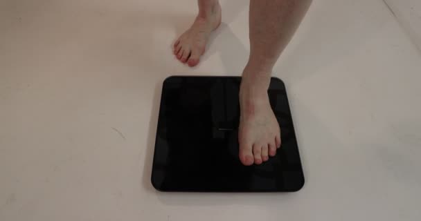 Мужские ноги идут к электронной шкале, чтобы взвеситься против белого пола, весом 87,1 кг в диете и клинике по борьбе с ожирением. Концепция здоровья и хорошего самочувствия - Кадры, видео