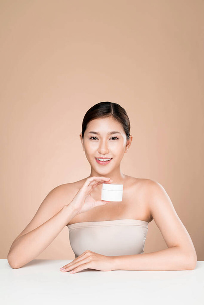 Ardent woman smiling holding mockup product for advertising text place, light grey background. Concept of healthcare for skin, beauty care product for advertising. - Fotoğraf, Görsel