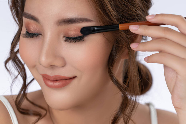 Closeup gorgeous young woman putting black mascara on her long eyelashes with brush. Beauty cosmetic concept. Female model with perfect skin. - Zdjęcie, obraz