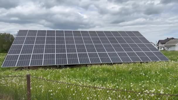 Solar power plant in cloudy weather on a field with dandelions in the summer - Felvétel, videó