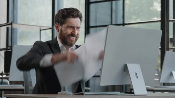Adult bearded Caucasian angry businessman tired unhappy mad man sit at desk feel stress with paperwork deadline upset trouble with work throwing papers hate job nerves difficult startup worry. High - Materiaali, video
