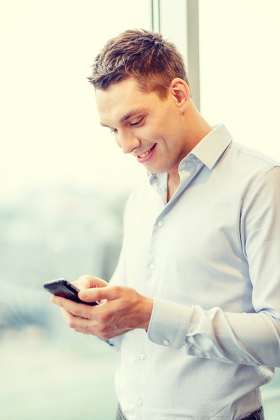 smiling businessman with smartphone in office - Foto, Imagen