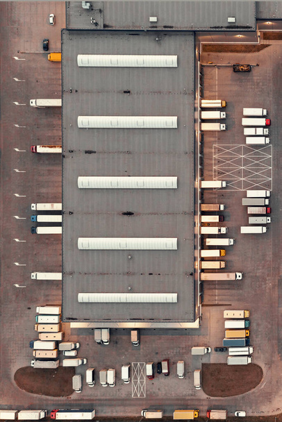 Αεροφωτογραφία αποθήκης με εμπορεύματα. Logistics κέντρο στη βιομηχανική ζώνη της πόλης, πολλά φορτηγά περιμένουν για φόρτωση στην αποθήκη logistics - Φωτογραφία, εικόνα