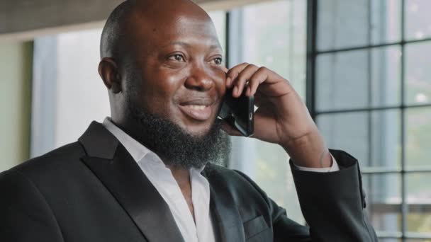 Bearded african middle-aged businessman american consultant salesman talk mobile phone in office consult client remotely distance call discuss business startup make order use wireless cell connection - Footage, Video
