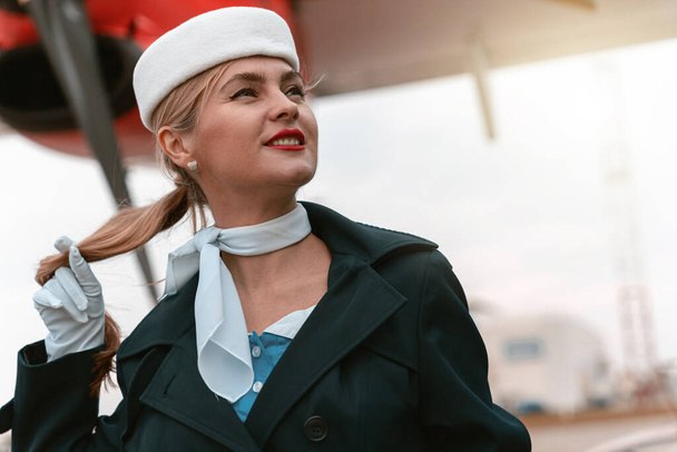 Woman flight attendant standing near airplane at airport and looking away. Blurred background - Foto, immagini