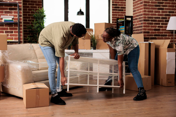 Married people unpacking furniture to move in rented apartment flat together, enjoying household relocation. Settling in new property bought on mortgage loan to start beginnings. - Fotoğraf, Görsel