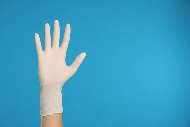 Doctor wearing medical gloves on light blue background, closeup. Space for text - Φωτογραφία, εικόνα
