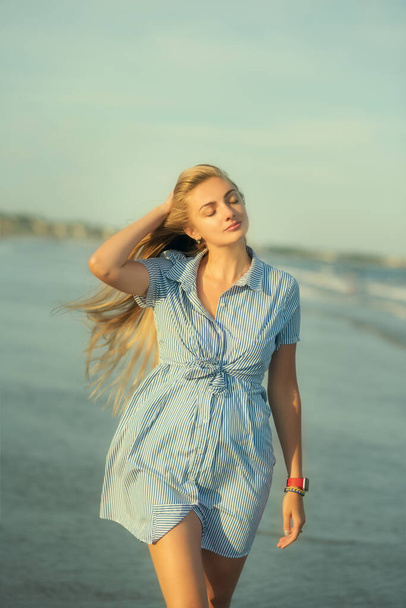 Girl with long hair on the sea coast in sunlight. Relaxed peaceful state while walking on the sea. - Foto, immagini