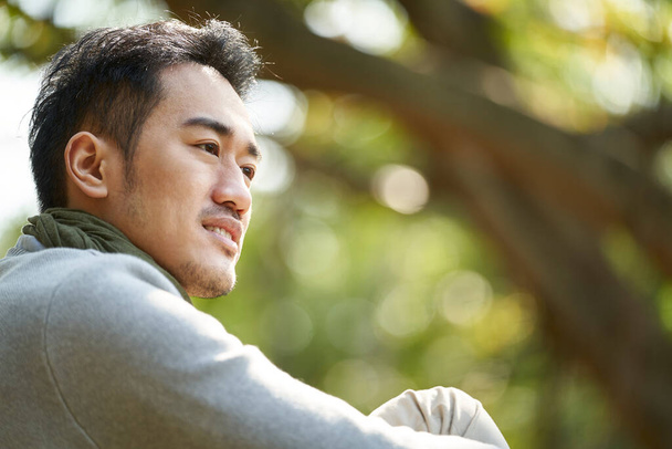 outdoor portrait of a young asian adult man, side view - Foto, imagen