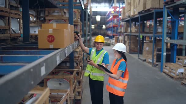 Young Asian woman worker using barcode scanner checking goods and box shelf stock in the warehouse factory store, co-worker man counting check stock. Warehouse Logistic concept. - Video, Çekim
