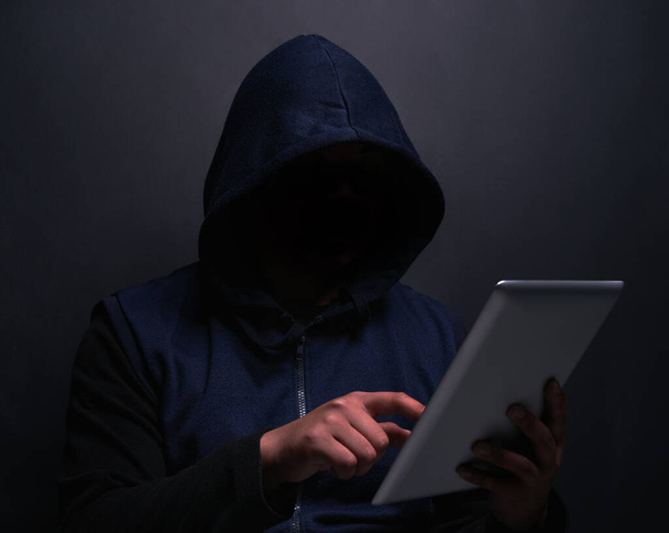 Кем должна быть моя следующая жертва. неузнаваемый хакер, использующий цифровой планшет на темном фоне - Фото, изображение