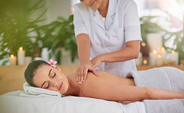 Unwind and enjoy the tranquil times. an attractive young woman enjoying a back massage at a spa - Foto, imagen