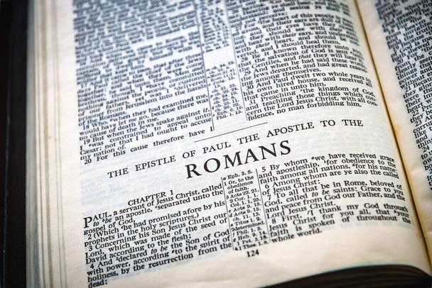 Close up of Holy Bible page, shallow depth of field with focus on book chapter heading, Romans - Foto, imagen