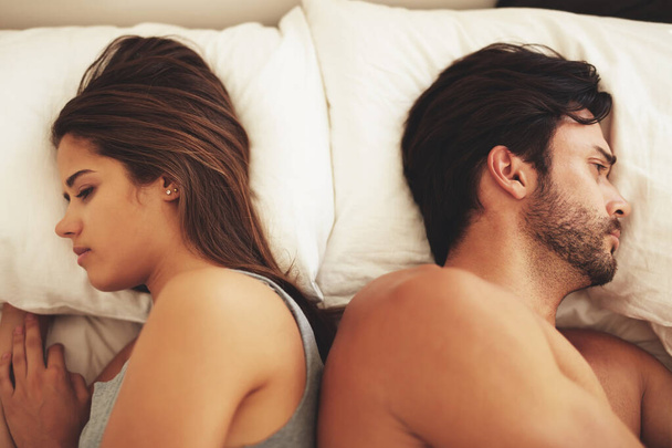 Somethings gone wrong. a young couple lying in bed and ignoring each other - Photo, Image