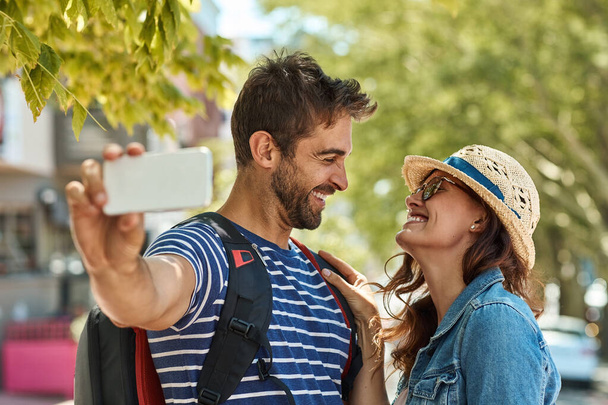 I dont want to see the world with anyone else. a happy tourist couple posing for a selfie while exploring a foreign city together - Foto, imagen