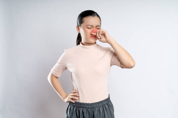 Asian woman was sick with fever, sneezing and rubbing her nose with red spot, standing isolated on white background. - Foto, Imagen