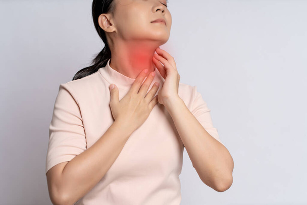 Asian woman was sick with sore throat, coughing sneezing and touching neck with red spot, standing isolated on white background. - Photo, Image