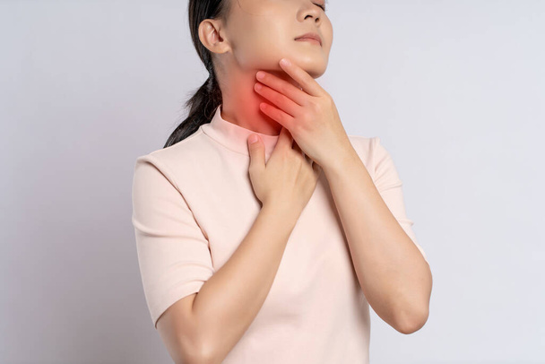 Asian woman was sick with sore throat, coughing sneezing and touching neck with red spot, standing isolated on white background. - Photo, Image