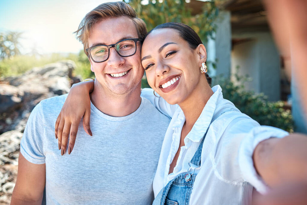 Selfie of interracial couple in love, smile and romantic date with care, bond and relax in summer outside. Portrait of happy boyfriend and girlfriend on holiday with special vacation photo together. - 写真・画像